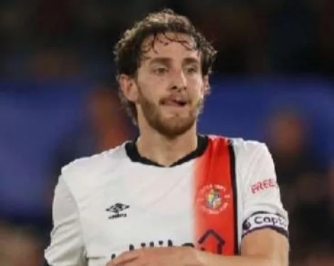 Tom Lockyer, jogador do Luton Town, reage após sofrer uma paragem  cardíaca no relvado